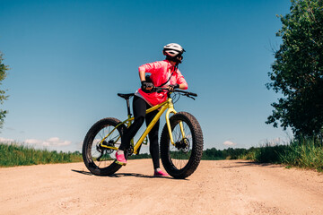 Fat-tire bike in summer driving through the hills. Woman is posing with a fat bike in the forest....