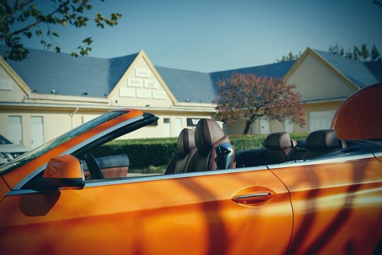 an open orange luxury sport car Stop at the shopping center near the roadster