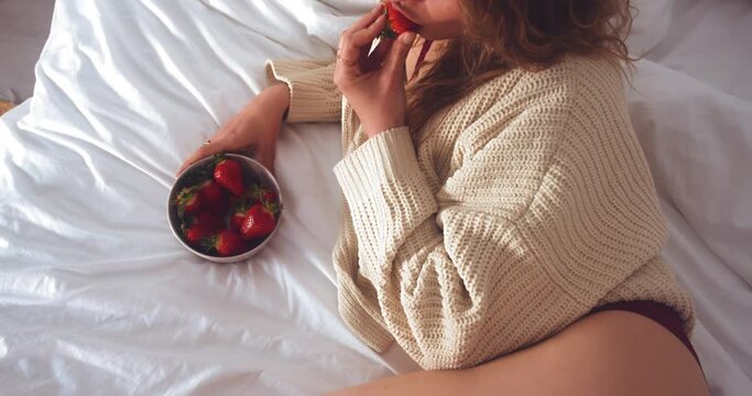 Crop View Of A Sexy Woman Eating Fresh Strawberries While Lying In Bed. High Angle Shot