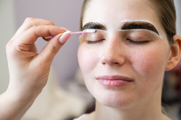 The master paints the eyebrows of a woman.