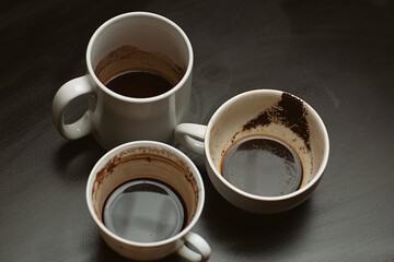Dirty multi-colored cups, mugs, glasses after different types of coffee on a black wooden table left after morning coffee drinking , coffeeshop style