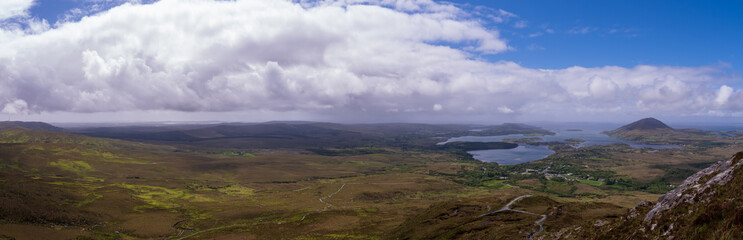scenic panoramic vista over Connemara National Park with white clouds and blue sky in Spring