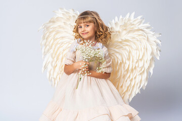 charming little girl with curly hair, dressed in an angel costume with big wings and flower crown....