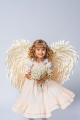 charming little girl with curly hair, dressed in an angel costume with big wings and flower crown....