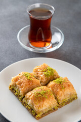 Pistachio baklava on a white plate with Turkish tea