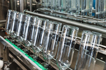 Row of empty glass bottles on automatic conveyor at plant