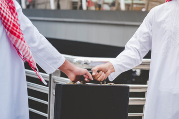 Arab Businessman shaking hands together. Teamwork business partner wear Muslim dress Shake Hands with Partnership Concept. Success UAE diversity people trust make commitment by handshake