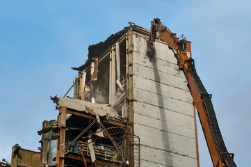 Fototapeta na wymiar Hydraulic scissors destroy abandoned industrial building