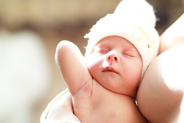 A newborn baby lies in her mother's arms. A beautiful baby of European appearance is sleeping.