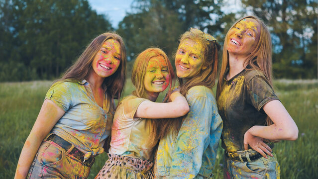 Cheerful girls posing smeared in multi-colored powder.
