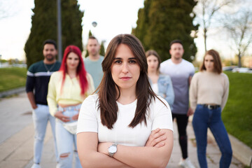 Confident woman looking at camera and smiling while standing with crossed arms in front of group of people. Friendship, union and team concept.