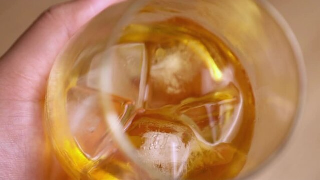 Man holding, swirling whiskey glass slow motion shot.
