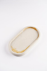 One concrete grey oval tablet with golden decoration ornament on white background, top view