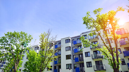 Ecological housing architecture. A modern residential building in the vicinity of trees. Ecology and green living in city, urban environment concept. Modern apartment building and green trees.