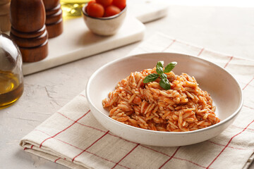Homemade italian dish pasta risoni with tomato basil sauce in a deep bowl on checkered napkin