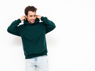Fototapeta premium Handsome smiling hipster model.Sexy unshaven man dressed in summer stylish green hoodie clothes. Fashion male with curly hairstyle posing in studio. Isolated on white
