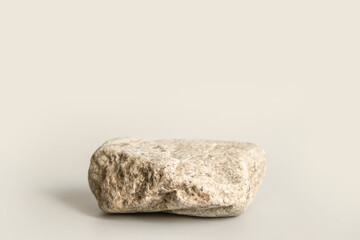 Natural stone stand for presentation and exhibitions on pastel beige background. Abstract podium for organic cosmetic products. Minimal style. Selective focus