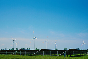 Windmill turbine generator and solar battery panels against blue sky, Concept of clean, renewable,...