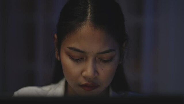 Close Up of Asian woman takes off her eyeglasses, rubs her eyes, and is tired of working in front of a computer for a long time.