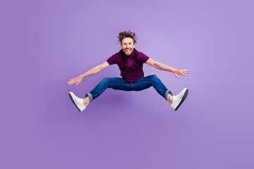 Full size photo of young excited man have fun jump up energetic isolated over violet color...