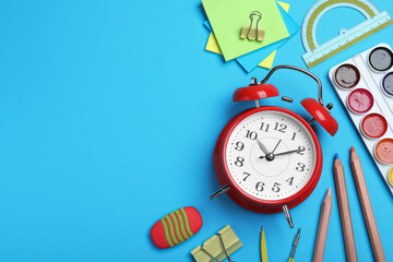 Flat lay composition with alarm clock and different stationery on light blue background, space for text. School time