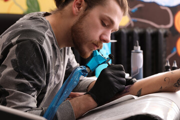 Professional artist making tattoo on hand in salon