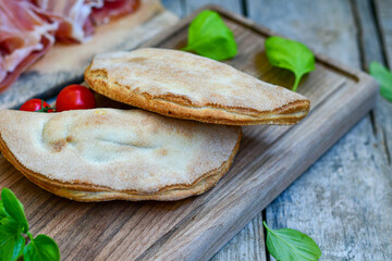 Home made italian calzone pizza with  prosciutto  tomatoes, mozzarella and parmesan cheese and fresh basil 