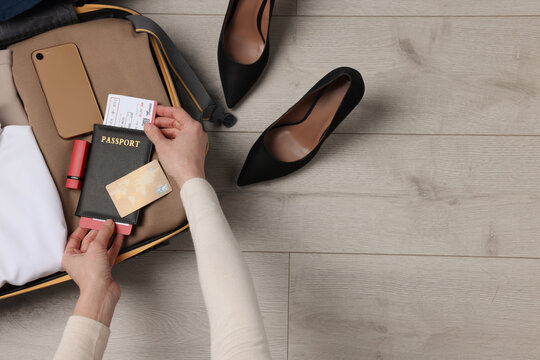 Woman packing suitcase on wooden floor, top view with space for text. Business trip planning