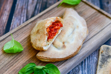 Home made italian calzone pizza with  tomatoes, mozzarella and parmesan cheese and fresh basil 
