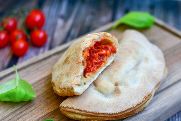 Home made italian calzone pizza with  tomatoes, mozzarella and parmesan cheese and fresh basil 