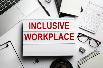 Flat lay composition of lightbox with phrase INCLUSIVE WORKPLACE on white table