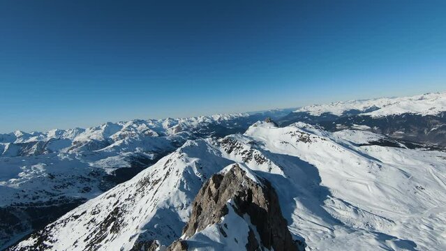 Aerial view sport FPV drone raising up top of mount. Beautiful peaks of the alps covered with snow cover