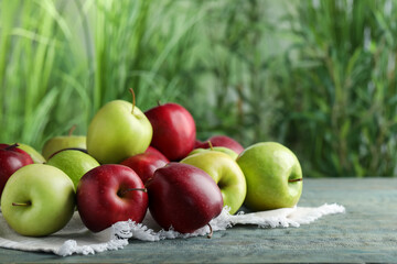 Fresh ripe red and green apples on light blue wooden table outdoors, space for text