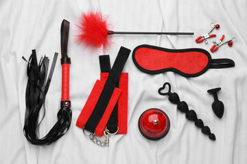 Sex toys and accessories on white fabric, flat lay