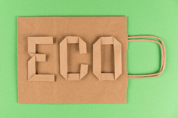 Eco kraft paper recycled bag with paper letters word ECO over green background. Street food take...