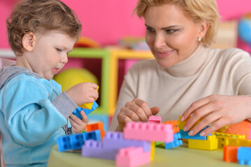 Mom plays with her little daughter sitting at the table