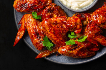 Baked spicy BBQ Chicken Wings smothered in barbecue sauce and serwed with White Sauce.  Close-up....