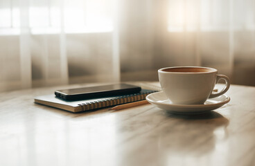 Close up view, white coffee cup with smart phone put on notebook and pencil on table in cafe near bright window in the morning, Vintage color tone, Concept holiday and relaxing
