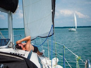 young person sunbathing on a sailboat under the sail