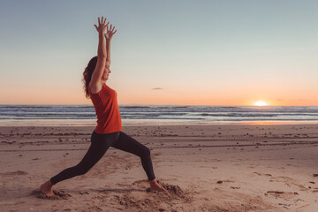 Fototapeta na wymiar woman on sand on beach performing yoga posture at dawn