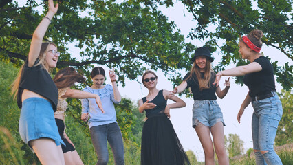 Girls are dancing outside the city on a picnic.