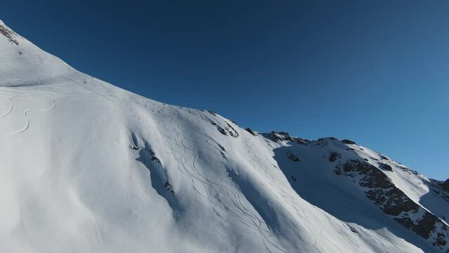 Aerial view sport FPV drone raising up top of mount. Beautiful peaks of the alps covered with snow cover