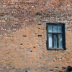 An abandoned old window in a dirty red brick wall