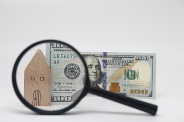 View of a house and a banknote through a magnifying glass, real estate purchase and insurance,...