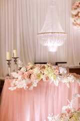 festive wedding table decoration with crystal chandeliers, golden candlesticks, candles and white pink flowers . stylish wedding day.