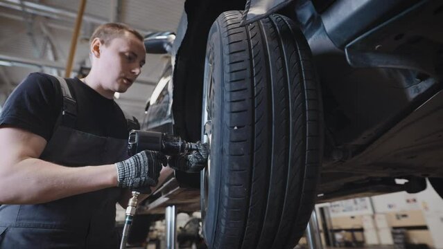 A mechanic at a car service station working with a wheel