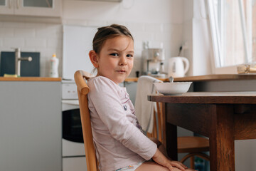 Caucasian preschool girl eating chocolate cereals with milk before school. Lifestyle morning breakfast top view