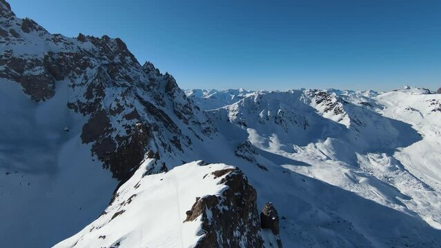 Aerial view sport FPV drone raising up top of mount. Beautiful peaks of the alps covered with snow cover