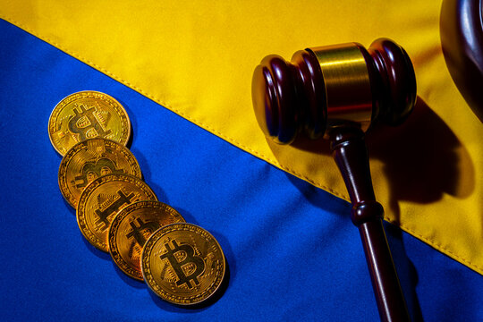 Gold cryptocoins bitcoin and judge gavel on the yellow blue flag of ukraine close up. Cryptocurrency on Ukrainian flag. Concept of the cryptocurrency market against the backdrop of the war in Ukraine. - Powered by Adobe
