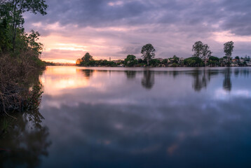 Fototapeta na wymiar riverside sunrise with cloud reflections